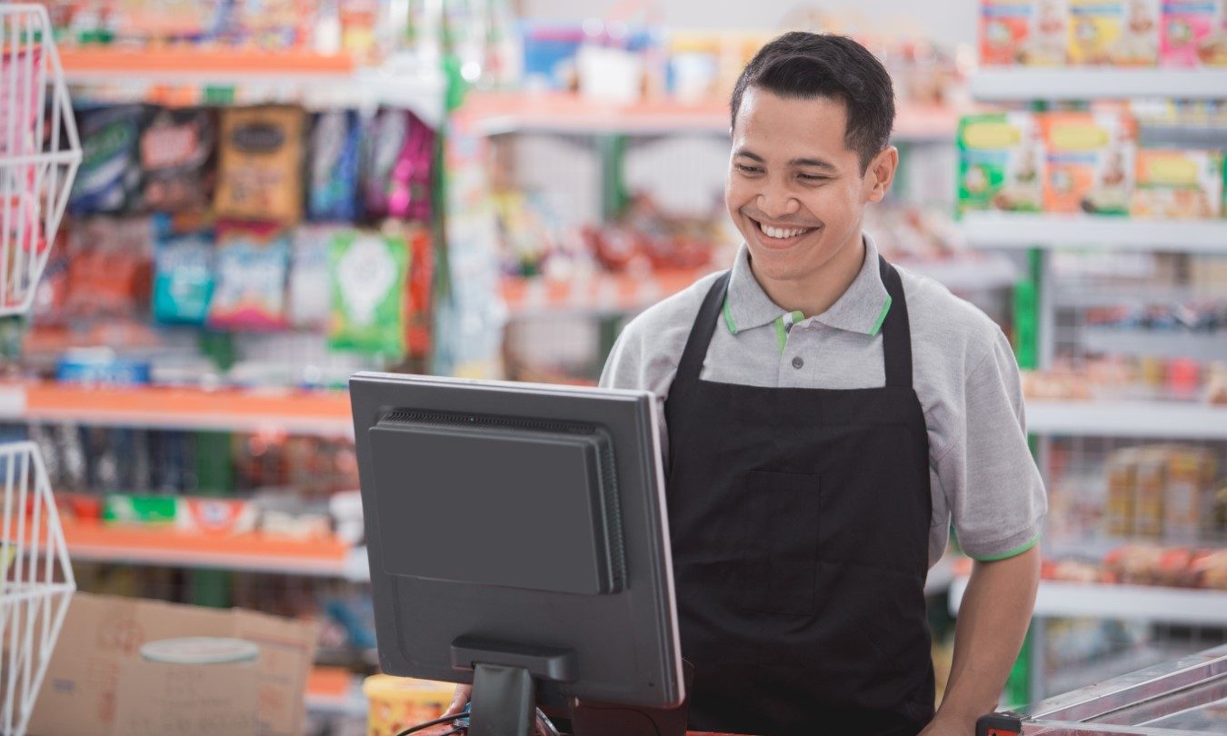 Asian male retail associate standing by POS terminal
